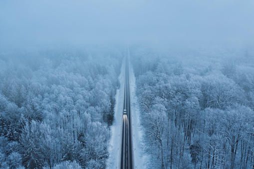 High angle view of a car on the road trough the winter forest with copy space