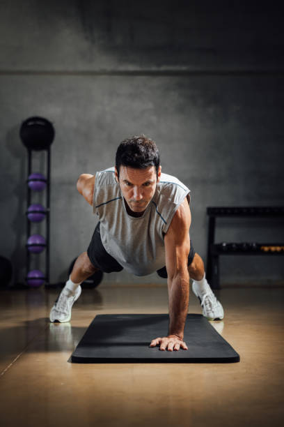 istock Strong caucasian man looks down while does push-ups with one hand in a dark gym. 1367329777