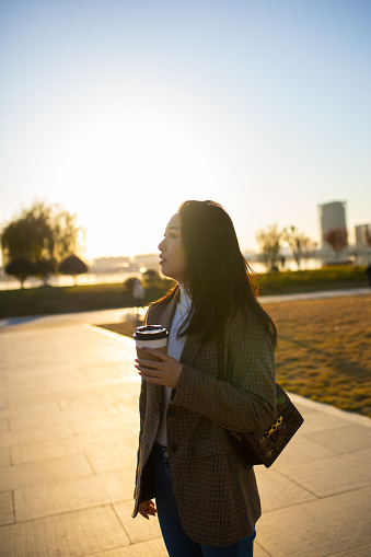 Young women  holding coffee cup walking in city morning