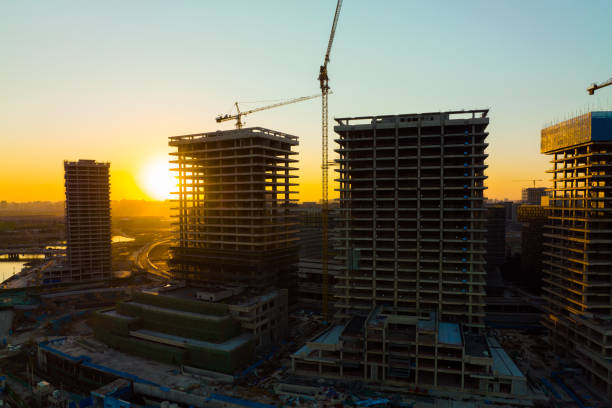 grúa de construcción con vista aérea en un sitio de construcción al atardecer - construction concrete large building activity fotografías e imágenes de stock