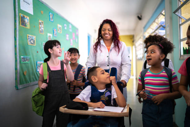 enseignant et élèves marchant dans le couloir de l’école - y compris une personne ayant des besoins spéciaux - teacher child student education photos et images de collection