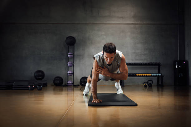 istock Strong caucasian man looks down while does push-ups with one hand in a dark gym. 1367330761