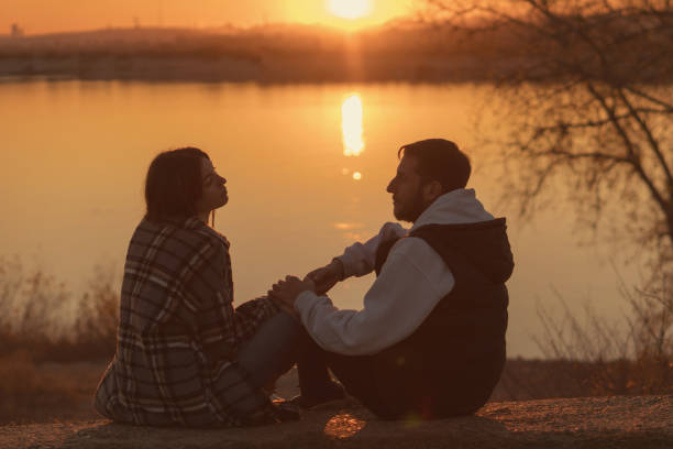 istock Couple sitting sunset lake 1367330934