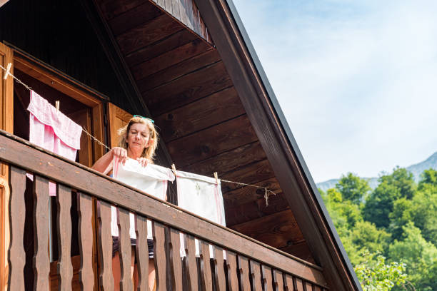 istock Woman on Cottage Balcony Hanging Washed Laundry 1367331210