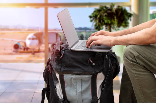 nómada digital escribiendo con computadora portátil en el aeropuerto - viaje de negocios fotografías e imágenes de stock