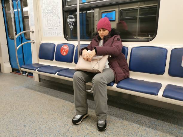 Moscow. Russia. January 25, 2022. A female passenger sleeps while sitting on a seat during a trip in a subway car.