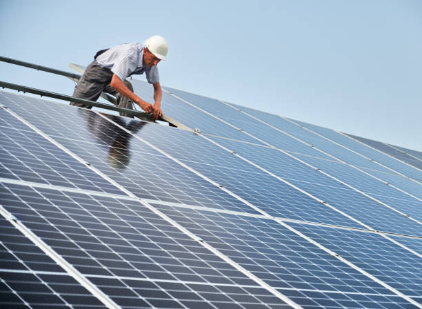 istock Male worker installing solar panels under blue sky. 1367335350
