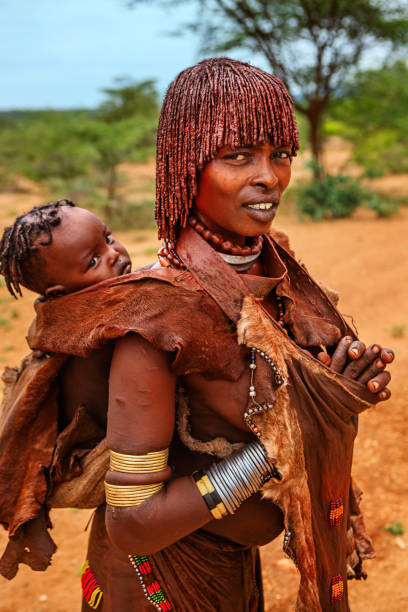 frau aus dem stamm der hamer, die ihr baby in äthiopien trägt, afrika - hamer woman stock-fotos und bilder