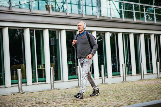 istock Mature businessman walking after work with headphones 1367335890