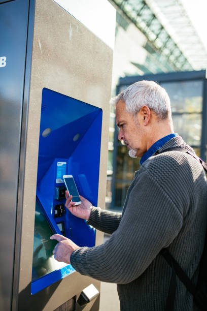 istock Mature businessman purchasing ticket on vending machine 1367336359
