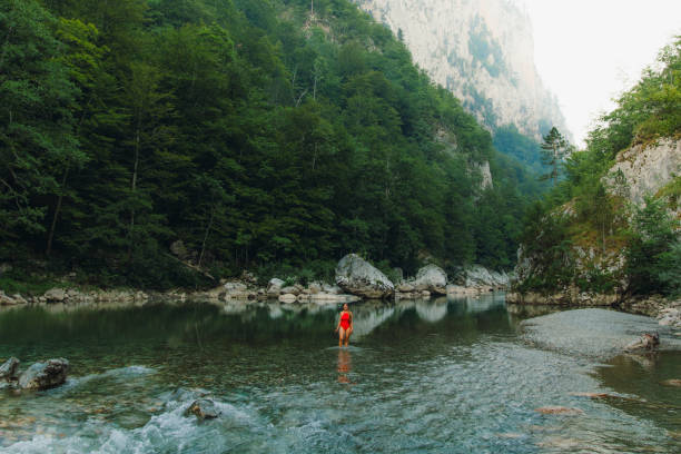 Female traveler refreshing in the river inside the scenic mountain canyon in Montenegro Young woman in red swimsuit exploring the Balkans, enjoying summer sunset in the canyon with mountain view at Durmitor National park women in skimpy bathing suits stock pictures, royalty-free photos & images