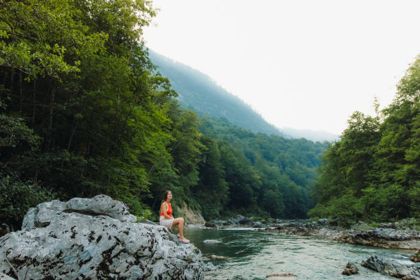 Female traveler sitting on the rock inside the scenic mountain canyon in Montenegro Young woman in red swimsuit exploring the Balkans, enjoying summer sunset in the canyon with mountain view at Durmitor National park women in skimpy bathing suits stock pictures, royalty-free photos & images