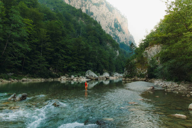 Female traveler refreshing in the river inside the scenic mountain canyon in Montenegro Young woman in red swimsuit exploring the Balkans, enjoying summer sunset in the canyon with mountain view at Durmitor National park women in skimpy bathing suits stock pictures, royalty-free photos & images