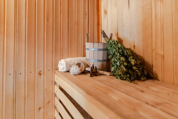 Traditional old Russian bathhouse SPA Concept. Interior details Finnish sauna steam room with traditional sauna accessories set basin birch broom towel aroma oil. Relax country village bath concept concepto de spa tradicional de la antigua casa de baños rusa. detalles interiores sauna finlandesa baño de vapor con accesorios de sauna tradicional juego lavabo escoba de abedul toalla aceite de aroma. concepto de baño de pueblo rural relax