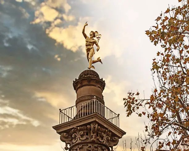 Stuttgart, Germany - Famous landmark: golden Hermes statue on a column near Schlossplatz at sunset