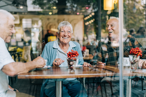 Shot of a group of elderly friends having coffee together. Group of cheerful seniors enjoying time together drinking coffee in cafe.