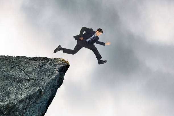 istock Man Looks Down After Running Over Edge Of Cliff 1367342374