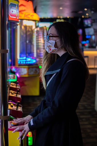 Young woman playing claw machine at local arcade