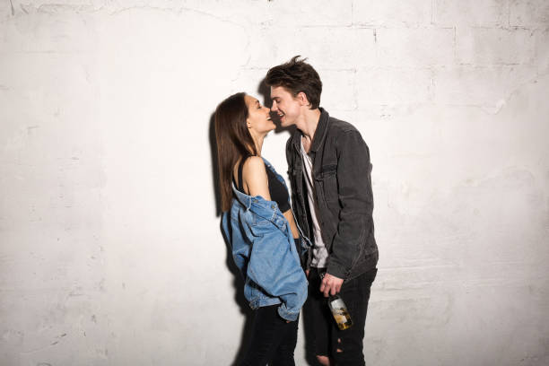 Picture of young hipster loving couple standing over gray background eating chocolate.