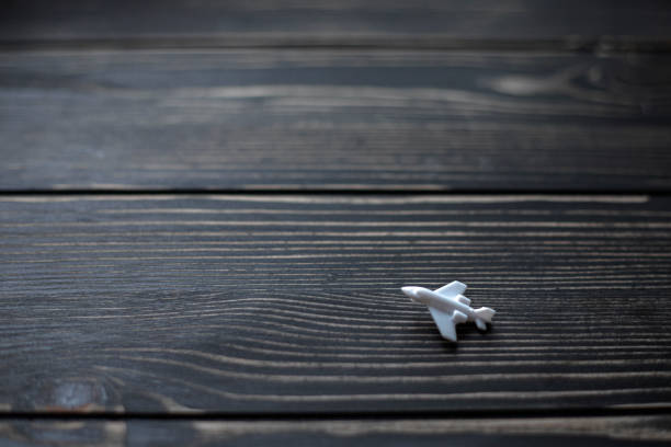 A small white toy airplane on a black wooden board background