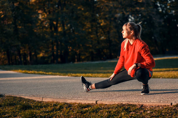 istock Young woman warming up and stretching before running in park. 1367347249