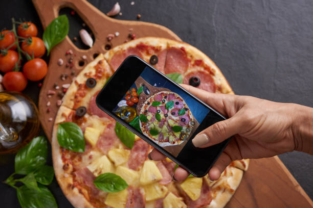 istock assorted food set on table. Italian pizza and pizza cooking ingredients on dark stone background. mozzarella, black olives, herbs and spices, take photo of pizza by smartphone. top view. 1367348802