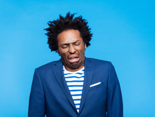 Portrait of displeased man Headshot of disgusted afro american man wearing blue jacket, striped t-shirt and eyeglasses. Studio shot on blue background. Portrait of designer. disgust stock pictures, royalty-free photos & images