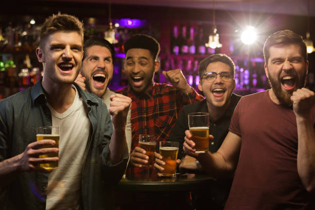 istock Four happy men holding beer mugs and gesturing 1367351792