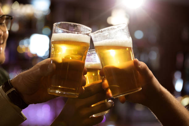 istock Men toasting with beer while sitting in pub together 1367351844