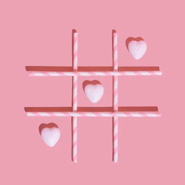Valentine's Day love concept. Pink and white bricks XO game with hearts on a pink background. Valentine's Day love concept. Minimal flat lay creative idea.