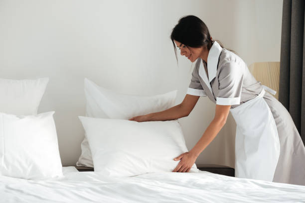 istock Young hotel maid setting up pillow on bed 1367356828