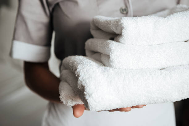 primer plano de una joven sirvienta sosteniendo toallas dobladas - limpiador fotografías e imágenes de stock