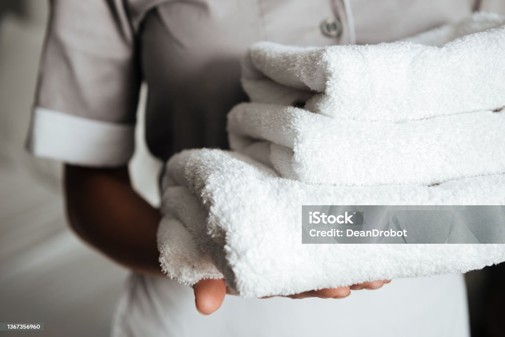 Close up of a young maid holding folded towels women indoors Housekeeping Staff Stock Photo
