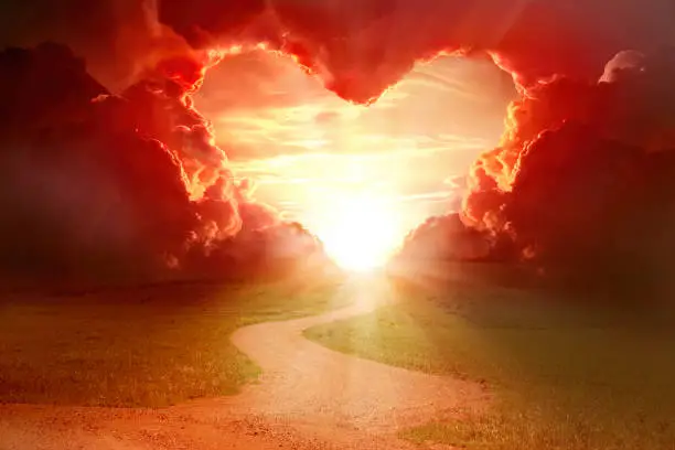 Red heart shaped sky at sunset. Beautiful landscape with road.Love background with copy space. Road to love