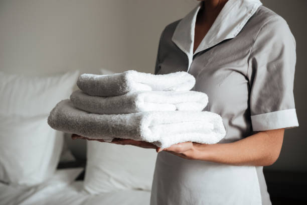 istock Young maid holding folded towels 1367358462