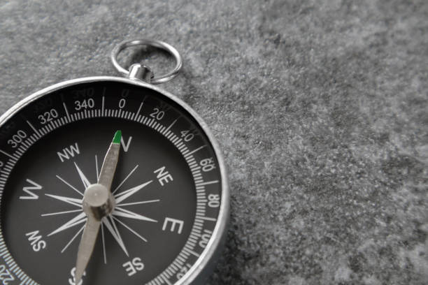 istock Magnetic compass laying on stone surface and pointing north selective focus. 1367361549