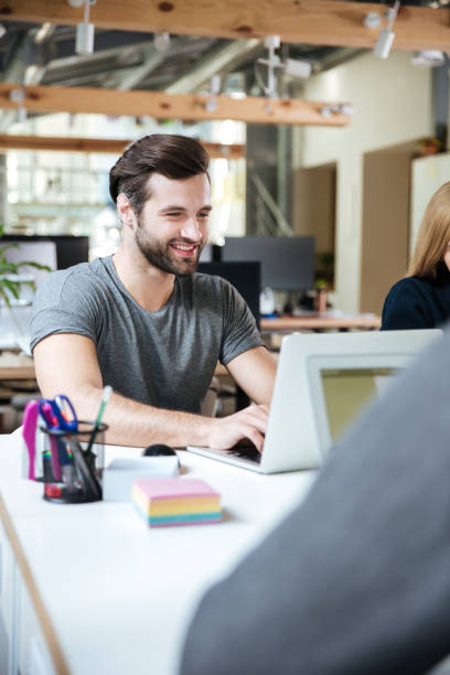 istock Happy young man sitting in office coworking 1367361687