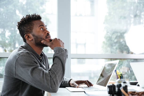 istock Handsome thinking serious young man sitting in office coworking 1367362184