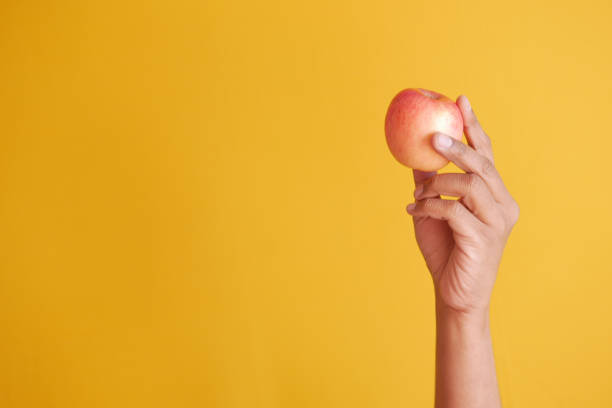 istock child boy hand hold a apple on yellow background 1367362247