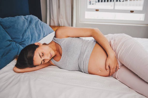 shot of a pregnant woman lying on her bed - labour room imagens e fotografias de stock