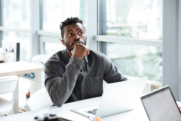 istock Handsome thinking serious young man sitting in office coworking 1367362362