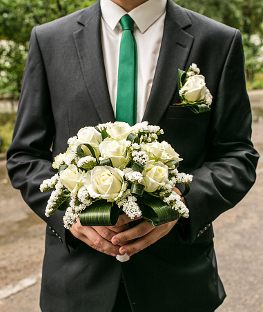 A man holds a wedding bouquet in his hands. Valentine's day concept. The concept of a wedding. groom with a bouquet. The groom in a suit holds a wedding bouquet. The bride's bouquet.
