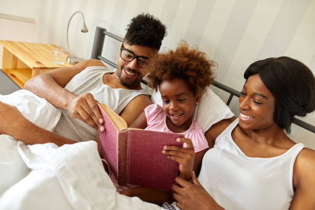 istock Happy family reading an interesting book in bed 1367365358