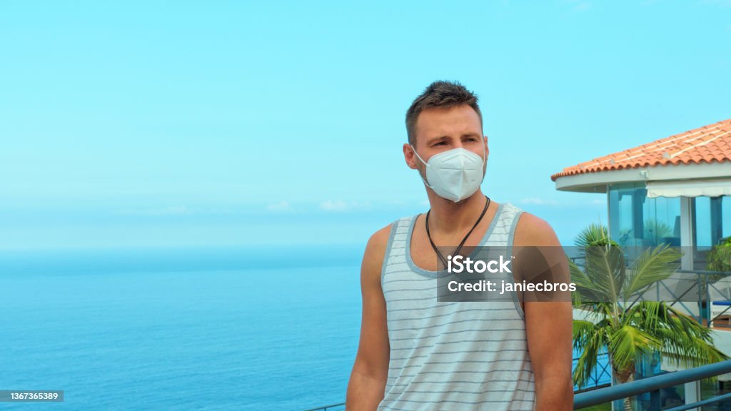 Man admiring a view from a patio. Wearing FPP2 mask Seascape seen from a patio, man's portrait 30-34 Years Stock Photo
