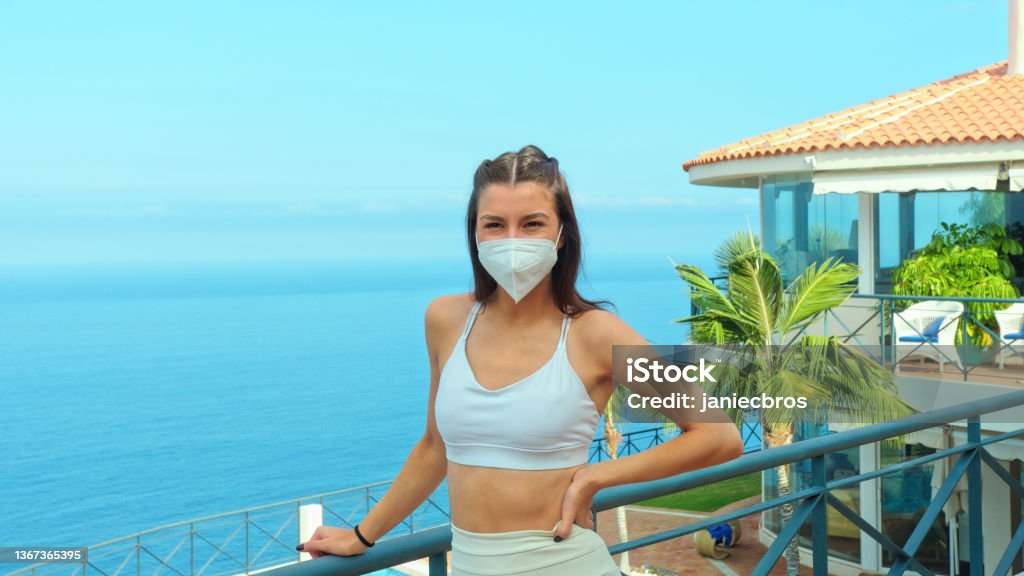 Woman admiring a view from a patio. Wearing FPP2 mask Seascape seen from a patio, woman's portrait 20-24 Years Stock Photo