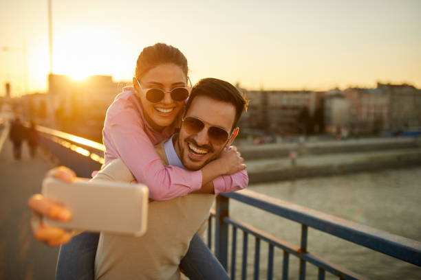 istock Smiling couple on bridge taking Selfie 1367365442