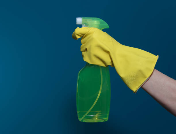 istock Hand in yellow rubber glove with a container of detergent. On blue background 1367369513