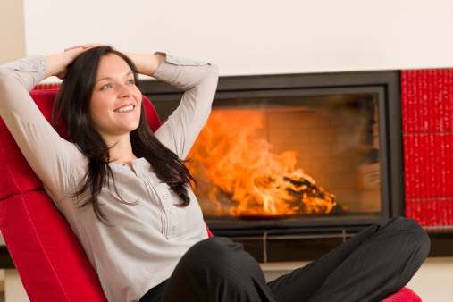Young woman relax on red armchair by home fireplace
