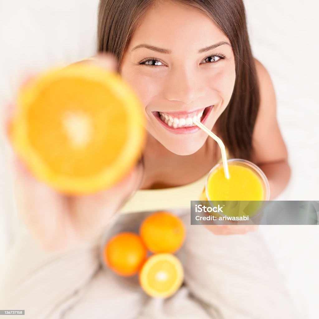 Orange juice drinking woman Woman drinking orange juice smiling showing oranges. Young beautiful mixed-race Asian / Caucasian model. See more: Orange Juice Stock Photo