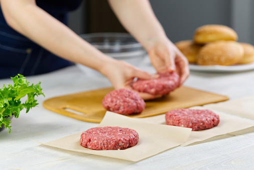 Woman's hand forming a beef meat for a hamburger party. Portioning ground meat. Homemade burgers. Making food at home. close up